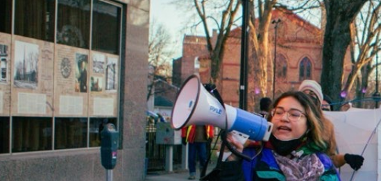 Photo of Chelsea Villalba speaking into a megaphone on Wall St. in Kingston NY
