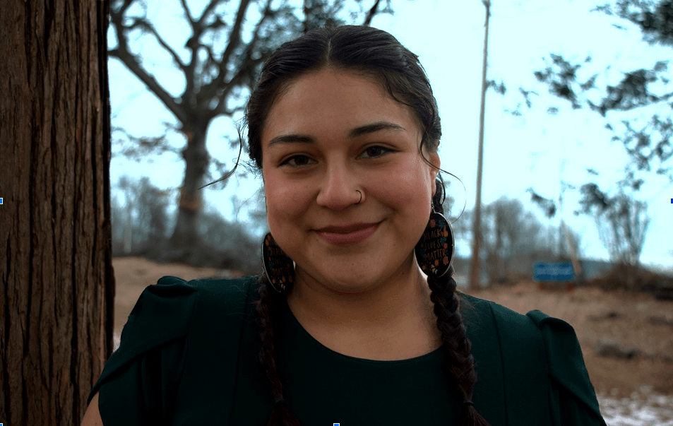 Photo of Chelsea Villalba, smiling at camera, trees in background